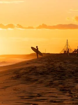 Surfer on the beach running during the sunset Stock Photos
