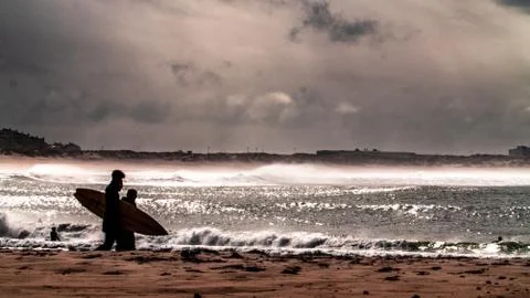 Surfer on the beach with sunset in the background Stock Photos