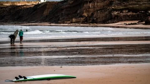 Surfer on the beach with sunset in the background Stock Photos