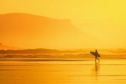 Surfer in the beach at sunset Stock Photos