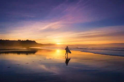 Surfer in the beach at sunset Stock Photos