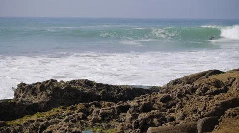 Surfer on blue ocean wave with rocks Stock Footage 59006230