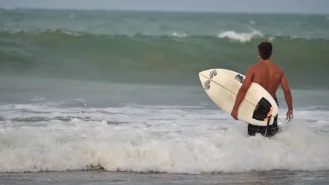 Surfer with a board looks at the big waves Stock Footage 258228712