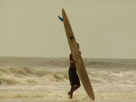 Surfer carries surfboard on beach  Stock Footage 8701401