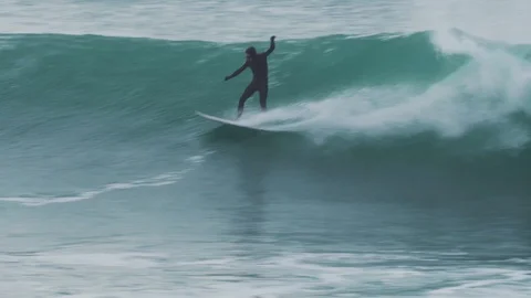 Surfer catches a large wave in Cornwall UK in the cold water on a winters Stock Footage 109469177