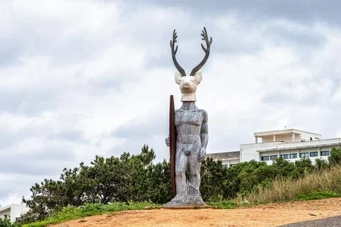 A surfer with a deer head installed at the lighthouse road of Nazare, Portuga Stock Photos