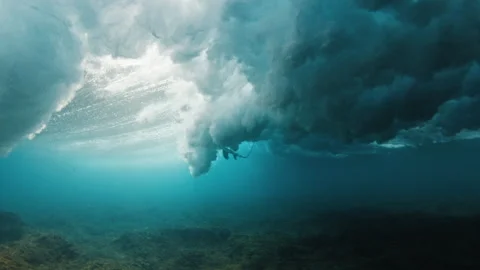 Surfer dives under the ocean wave with surfing board and passes it. Underwater Stock Footage 324960933