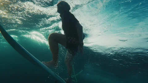 Surfer dives under the ocean wave with surfing board and passes it. Underwater Stock Footage 324963165