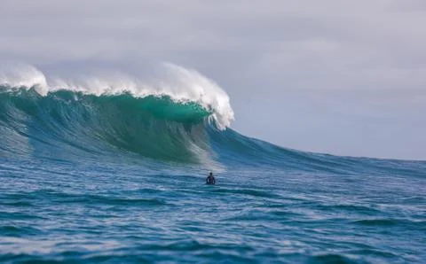 Surfer dwarfed by giant waves breaking off the coast of South Africa Stock Photos