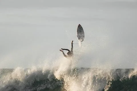 Surfer falling while trying to jump a wave losing his surfboard Stock Photos