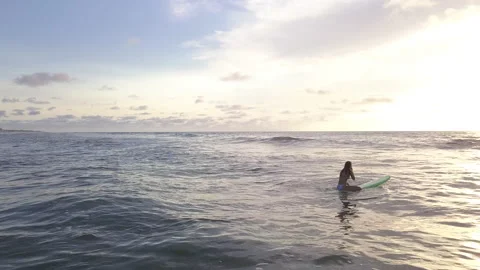 Surfer floating in ocean waiting for a wave at sunrise Video stock 140361071