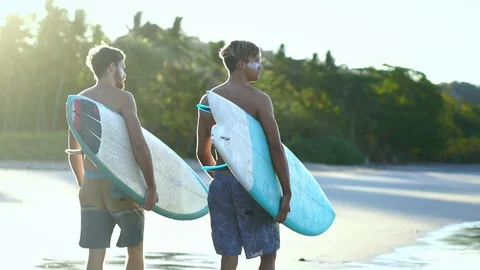 Surfer friends walk with surfboard on beach at sunrise in slow motion Stock Footage 108564759