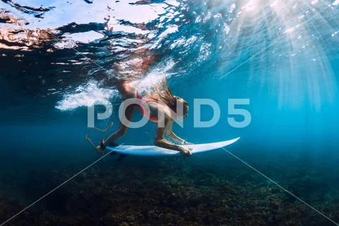 Surfer girl in bikini with surfboard dive underwater with under barrel ocean Stock Photos