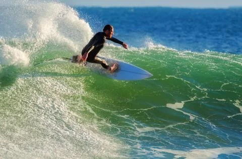 Surfer gracefully slicing through a steep, green wave Stock Photos