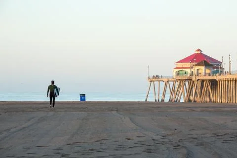 Surfer heading out to catch waves at the beach in the morning light Foto stock