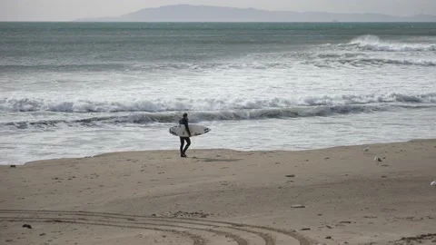 Surfer heads out for massive waves caused by the Santa Ana winds in Ventura, CA Stock Footage 144796945