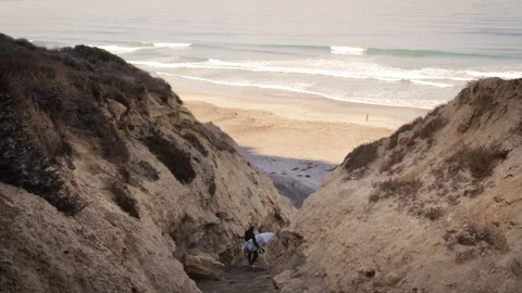 Surfer Hiking Down to Hidden Beach in the Early Morning Mist Stock Footage 90970531