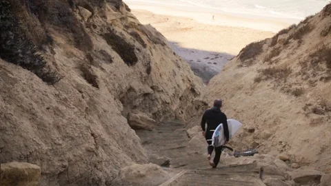 Surfer Hiking Down to Hidden Beach in the Early Morning Mist Stock Footage 90970538