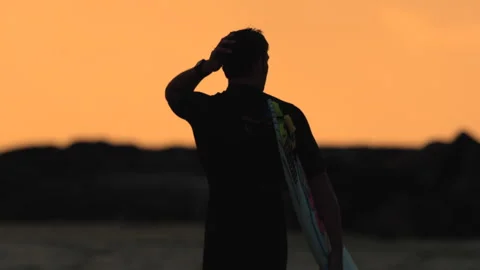 A surfer with his board at sunset Stock Footage 264149374