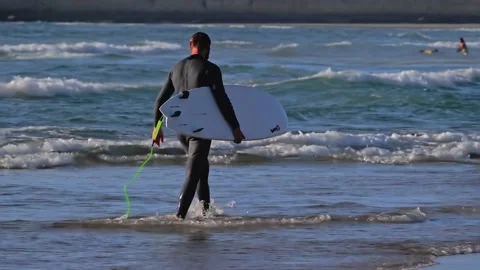 Surfer with his surfboard on the beach Stock Footage 138025428