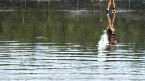 Surfer with his surfboard reflected on the water surface Stock Footage 100089506