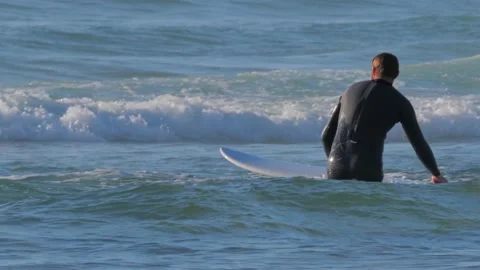 Surfer with his surfboard walking towards ocean at sunset Stockbeeldmateriaal 138025042