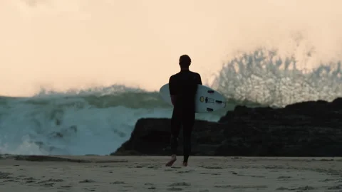 Surfer holding onto his board while looking at the huge waves Stock Footage 264149284