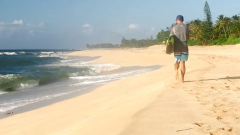 Surfer holding surfboard and walking on the beach Hawaii Stock Footage 71837288