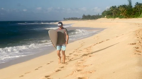 Surfer holding surfboard and walking on the beach Hawaii Stock Footage 71837440