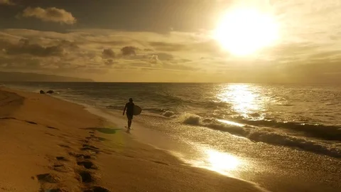 Surfer holding surfboard and walking into water during sunset Stock Footage 71837497