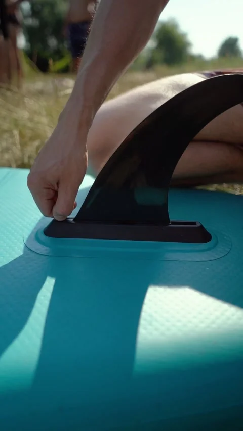 A surfer inflates his sup board before a swim on the river Видео 330894785