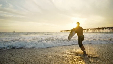 Surfer jumping into sea at sunset Stock Footage 105621993