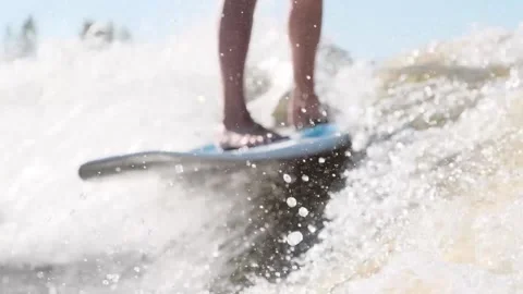 Surfer jumping at speed in waves using wakeboard splashing water drops to camera Stock Footage 165691604