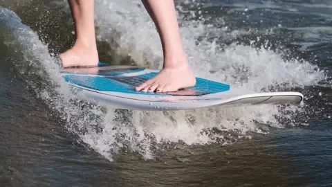 Surfer jumping at speed in waves using wakeboard splashing water drops to camera Stock Footage 165691640