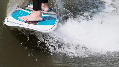 Surfer jumping at speed in waves using wakeboard splashing water drops to camera Stock Footage 165691670