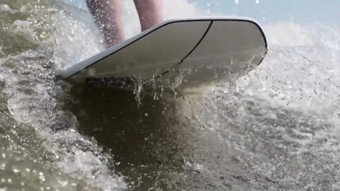 Surfer jumping at speed in waves using wakeboard splashing water drops to camera Stock Footage 165691697