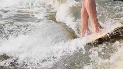 Surfer jumping at speed in waves using wakeboard splashing water drops to camera Stock Footage 165691730