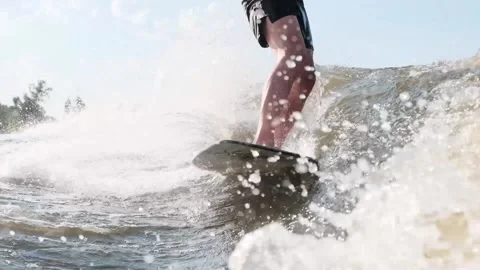 Surfer jumping at speed in waves using wakeboard splashing water drops to camera Stock Footage 165691769