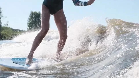 Surfer jumping at speed in waves using wakeboard splashing water drops to camera Stock Footage 165691870