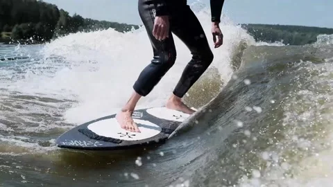 Surfer jumping at speed in waves using wakeboard splashing water drops to camera Stock Footage 165691891