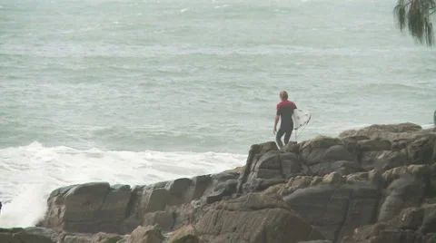 Surfer jumps off rocks Stock Footage 5500623