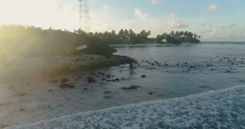 Surfer leaving or getting out of the sea water with sun flare beam while Stock Footage 131740159