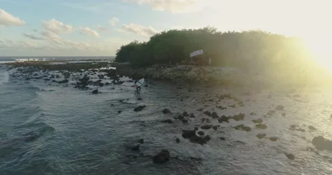 Surfer leaving or getting out of the sea water with sun flare beam while Stock Footage 131740858