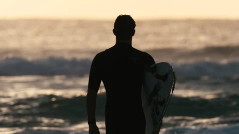 Surfer looking at the ocean with his board then his hand Stock Footage 264149847