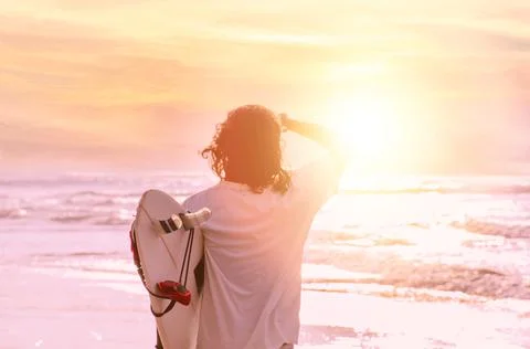 Surfer looking at waves at sunset Stock Photos
