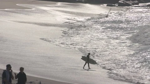 A Surfer in Malibu california jumps in the ocean in the early morning on Stock Footage