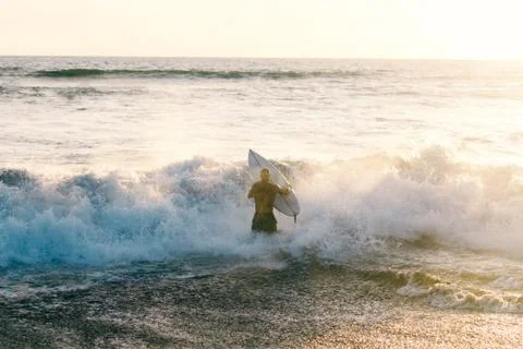 Surfer man entering the ocean Stock Photos