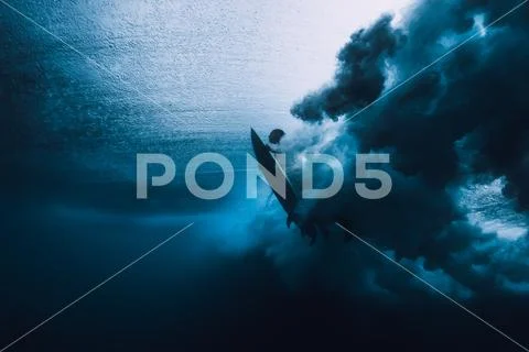 Surfer man with surfboard dive underwater with under ocean wave. Stock Photos