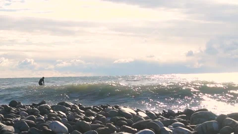 A surfer with a paddle tries to cope with a wave on a sunny day Stock Footage 169810422