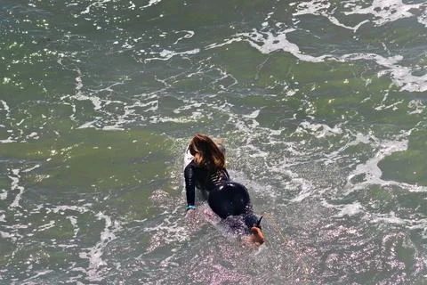 Surfer paddling forward through active shorebreak waves Stock Photos